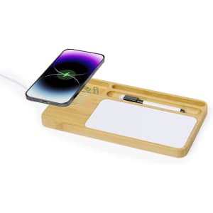 A bamboo wireless charger with compartments for a phone, a pen, and a notepad. The phone displays a purple screen.
