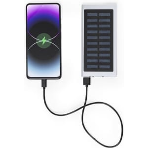 A power bank in white and silver, featuring a solar panel, connected to a smartphone via a charging cable.