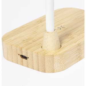 A wireless charger lamp with a bamboo base and a white lamp post. It features a charging port on the side.