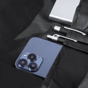 A black backpack interior featuring a smartphone, a power bank, and two pens. There is a logo present.
