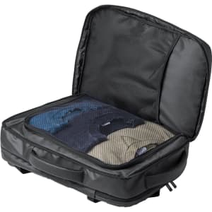 A black document bag backpack with an open compartment displaying neatly folded clothes inside.