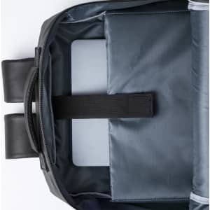 An open black backpack with a grey interior, featuring a compartment secured by a strap.