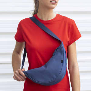 A navy blue shoulder bag worn across the body, featuring a sleek design and a single strap.