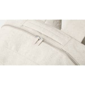 A cream, textured backpack featuring a zip closure and padded straps. It includes a logo on the side.