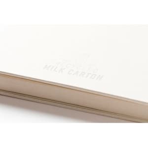 A notebook made from recycled milk cartons, featuring a light-coloured cover and subtle branding.
