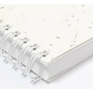 A notebook with a speckled white cover and spiral binding, featuring a textured surface and blank pages.