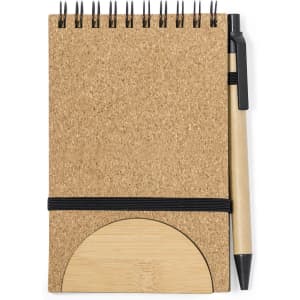 A cork notebook with a spiral binding, accompanied by a black pen and a circular bamboo bookmark, featuring a black elastic band.