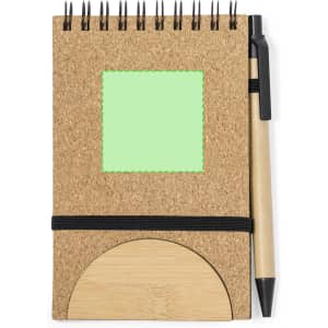 A cork notebook with a green sticky note area, featuring a bamboo holder and a black pen attached.