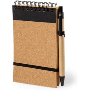 A cork-covered notebook with a black spiral binding and a black pen attached with an elastic band.