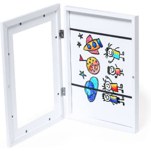 A white picture frame with an open front, showcasing a colorful children's drawing inside. It features a logo.