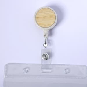 A badge reel with a bamboo-style top and clear plastic holder for ID cards. Features a silver clip and retractable cord.