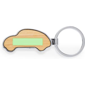 A silver keyring shaped like a car, featuring a wooden surface with a light green area.