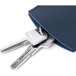 Close-up of a navy keyring with two silver keys partially visible, nestled in a soft fabric pocket.
