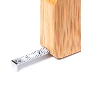 A tape measure with a silver metal end extending from a wooden bamboo casing.