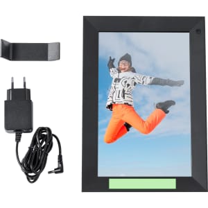 A digital photo frame in black, displaying a photo of a person jumping, accompanied by a power adaptor and a wall mount.