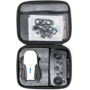 A compact black carrying case containing a white drone and a black remote controller, with printed materials inside.
