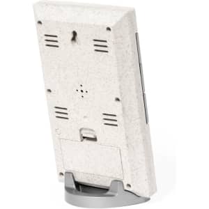 A weather station with a textured white back, featuring vents and a stand for support. It includes a small branding logo.
