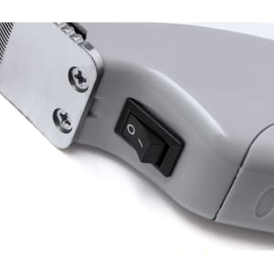 A close-up of a grey hair trimmer's toggle switch, with metal detailing visible on the edge.
