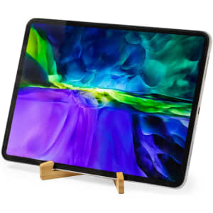 A wooden phone stand supports a tablet displaying a vibrant, abstract screen image in blue, green, and purple tones.