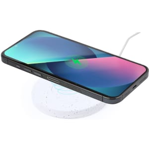 A wireless charger in white with a phone placed on top, featuring a bright, colourful screen. The charger has a logo.