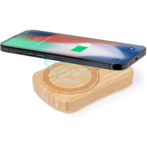 A wooden wireless charging pad with a smartphone positioned above it, showcasing a sleek, modern design.