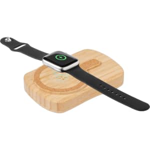 A black smartwatch resting on a wooden charging pad. The pad has a circular design.