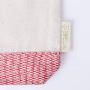 A toiletry bag in cream with a red textured bottom and a small tag indicating recycled cotton.