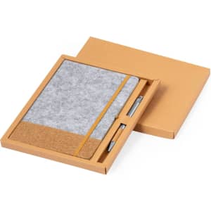 A grey notebook with a cork section and an elastic band, accompanied by a pen, presented in a cardboard box.