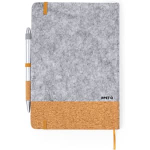 A grey notebook with a cork bottom and an orange elastic band, accompanied by a silver pen. It has a logo visible.