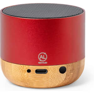 A small, round speaker in red metal with a bamboo base, featuring a black mesh top and ports on the side.
