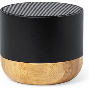 A speaker with a black top and a bamboo base, featuring a textured grill on the top. It has a minimalist design and a logo.
