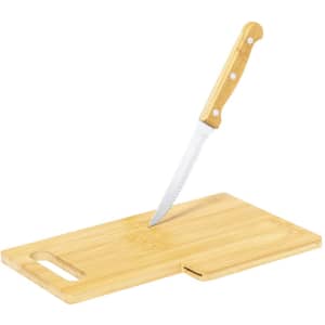 A wooden chopping board in a light bamboo finish with a serrated knife resting on it.