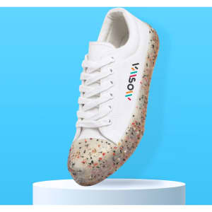 A white sneaker with a multicoloured speckled sole, featuring a logo on the side, displayed on a pedestal against a blue background.