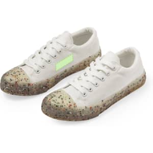 White trainers with a speckled translucent sole and a light green logo area. They feature a classic lace-up design.