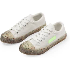 White sneakers with a speckled, translucent sole and a green accent, featuring a logo on the side.