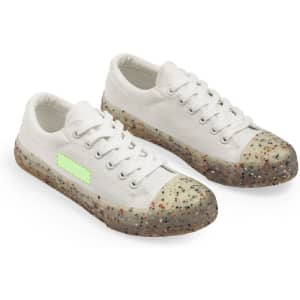 A pair of white trainers with a speckled translucent sole and a green accent on the side.