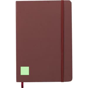 A brown notepad with an elastic band closure and a small green square on the front. A logo is also present.