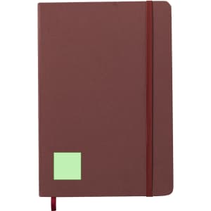 A brown notepad with a green sticky note, featuring an elastic band and a ribbon bookmark. It has a logo.