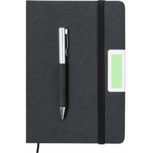 A dark grey notebook with a matching pen attached, featuring a logo and a green label on the side.