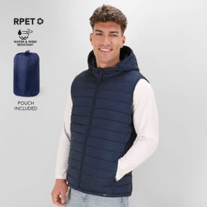 A navy blue padded vest with a hood, featuring a logo and a pouch for storage. The model is smiling while wearing it.