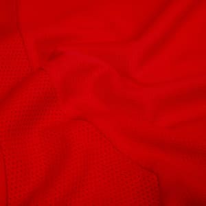 A vibrant red T-shirt featuring a textured mesh fabric and a brand logo.