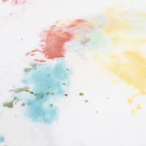 A white t-shirt with vibrant splashes of red, blue, yellow, and green paint-like patterns.