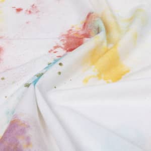 A white T-shirt with a vibrant, multicoloured abstract print featuring swirls of red, yellow, and blue.