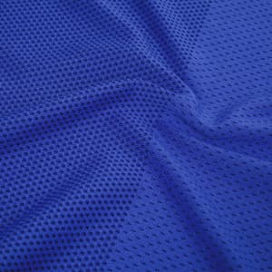 A textured blue fabric of a T-shirt featuring a mesh-like design and a logo.