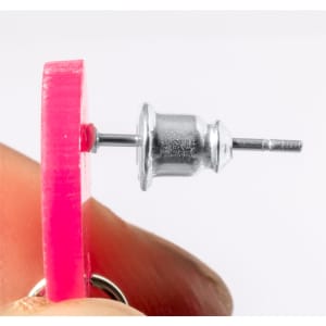 A pair of pink Kely earrings featuring a silver stud design, held between two fingers.