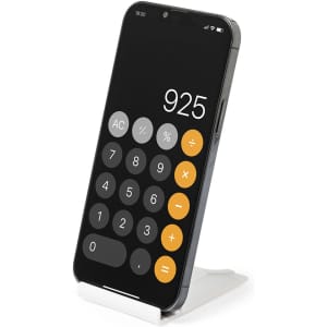 A smartphone on a white stand displays a calculator app with a black background and orange buttons.