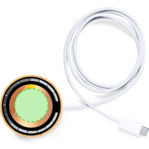 A wireless charger in circular shape with a wood rim and a white USB cable attached.