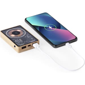 A wooden power bank in brown, connected to a black smartphone via a white charging cable.