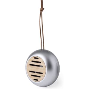 A round silver speaker with a wooden front and a hanging leather strap. It features multiple sound vents.