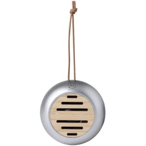 A round silver speaker with a wooden panel and a leather strap for hanging. It features a minimalist design and a logo.